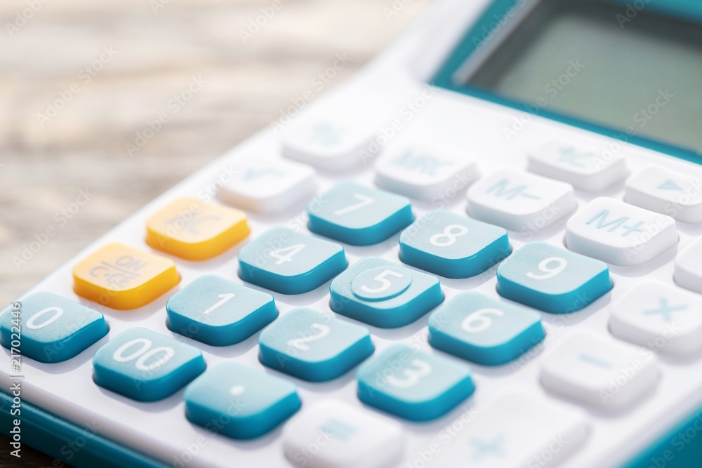 calculator focus at on press button keyboard. calculator colors blue yellow and white on wood table. concept calculate account finance. calculator focus at on press button keyboard. calculator colors blue yellow and white on wood table. concept calculate account finance.