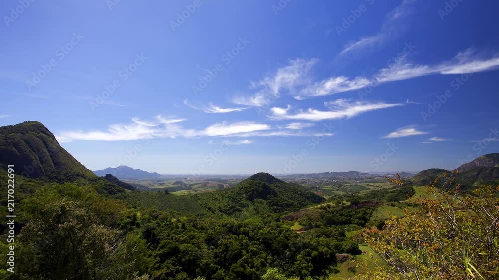Timelapse of a landscape with mountains and forests. City and pastures in the background. Blue sky with clouds. Timelapse of a landscape with mountains and forests. City and pastures in the background. Blue sky with clouds.
