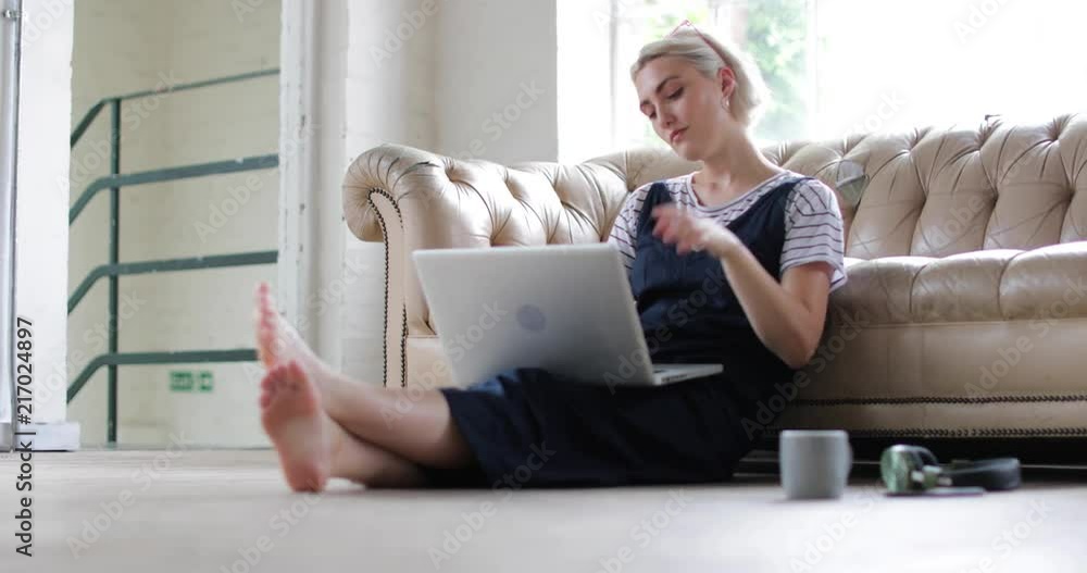 Millennial using laptop in a loft apartment Millennial using laptop in a loft apartment