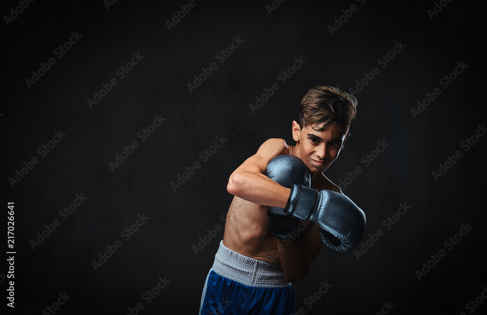 Handsome shirtless young boxer during boxing exercises, focused on process with serious concentrated facial.
