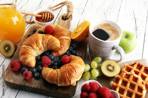 Delicious breakfast with fresh croissants and ripe berries on table