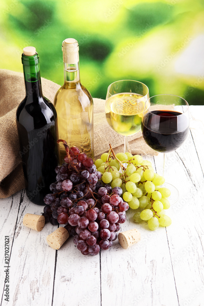 White wine and red wine in a glass with fall grapes, white woode