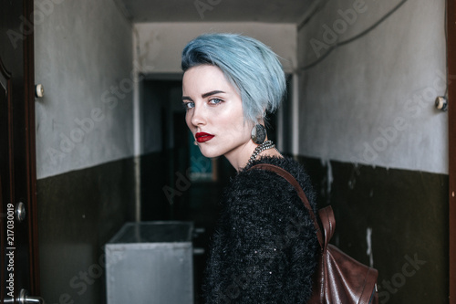 The girl with short blue fashionable hairstyle standing in an old corridor in Ukraine photo