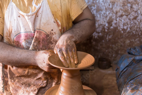 Man giving a shape to the hand made pottery on pottery wheel