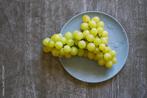 Healthy eating. White grapes in a blue plate on a dark natural background.