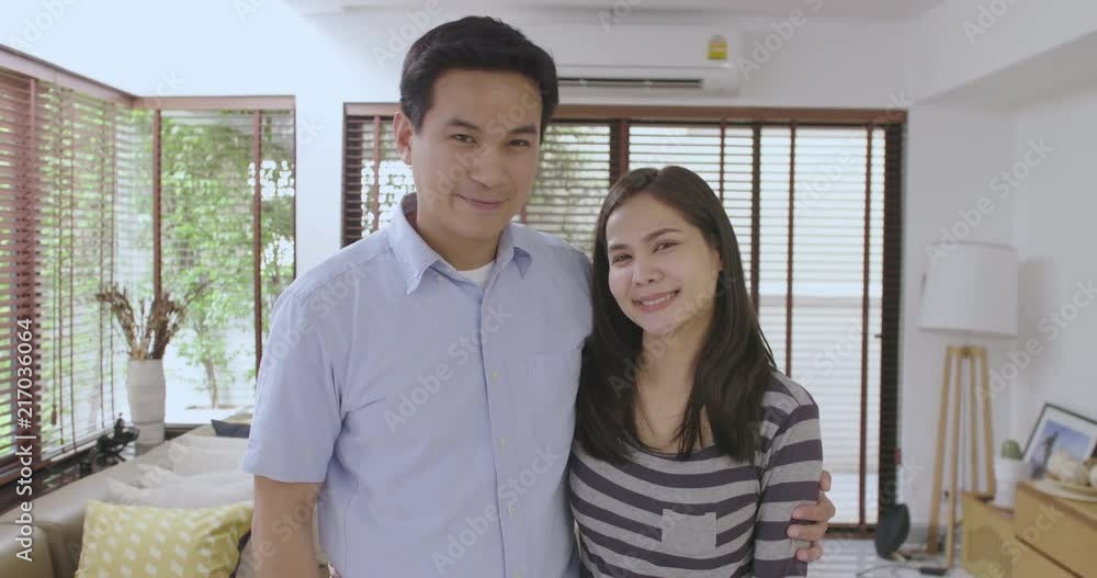 Portrait of happy young asian couple standing inside new home with keys Portrait of happy young asian couple standing inside new home with keys