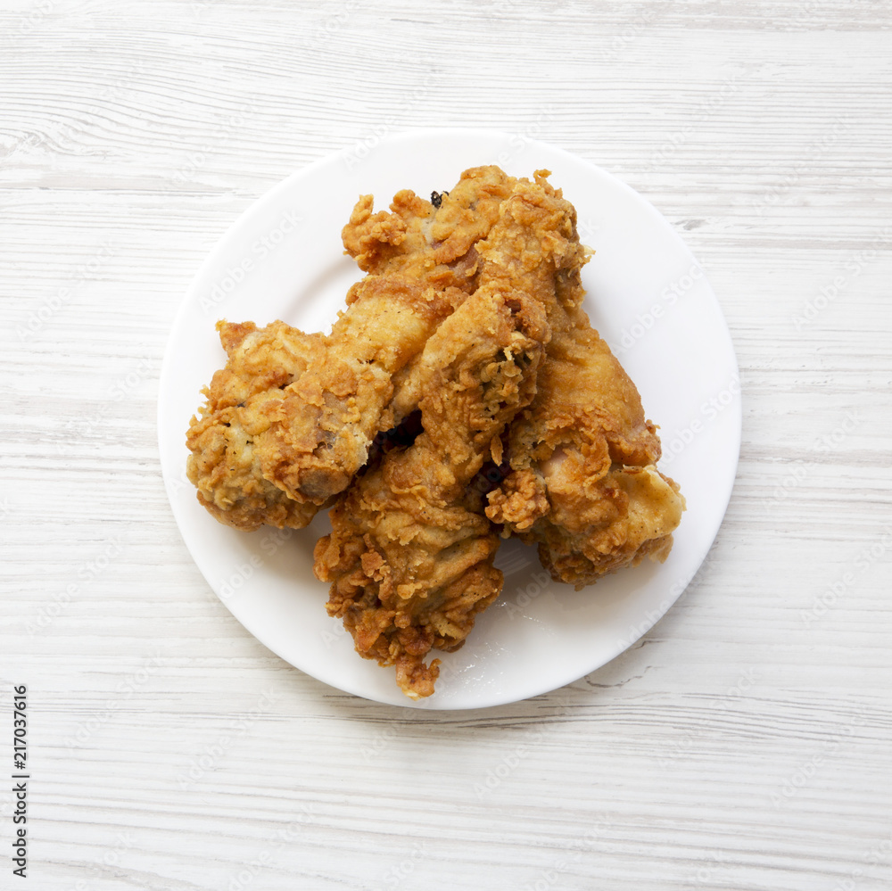 Fried chicken legs on a white round plate, top view. From above, overhead, flat lay. Fried chicken legs on a white round plate, top view. From above, overhead, flat lay.