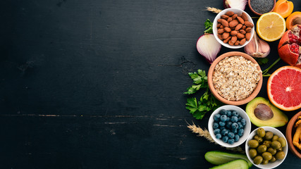 Healthy food clean eating selection: Vegetables, fruits, nuts, berries and mushrooms, parsley, spices. On a black background. Free space for text.