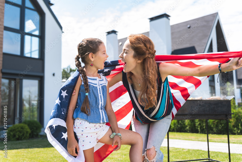 Obraz premium American patriots. Happy nice mother and daughter laughing while celebrating a holiday together