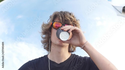 Young man standing in city park drinking coffee and smiling photo