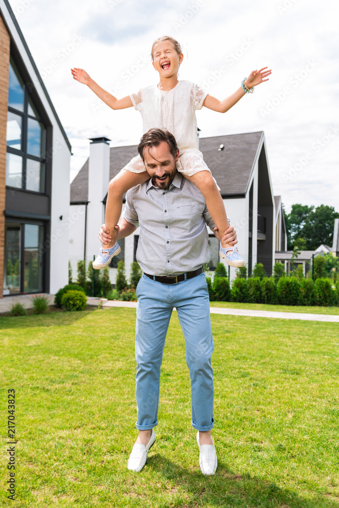 Childish fears. Nice pleasant girl sitting on her fathers shoulders while being afraid of height