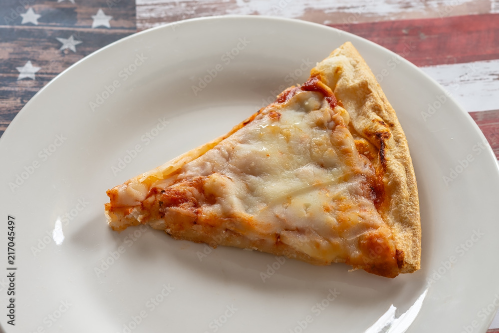 Slice of cheese pizza on white plate with USA flag background and room for text Slice of cheese pizza on white plate with USA flag background and room for text