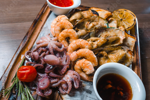 fried seafood squids, shrimps, mussels sauce on wooden board photo