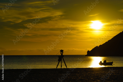 Camera taking picture of sunrise over sea surface