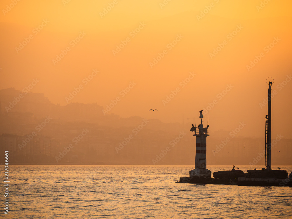 Sunset over the sea at modern city izmir, Turkey. Sunset or sunrise with seagull, lighthouse. the concept of tranquility, calm, rest and travel.