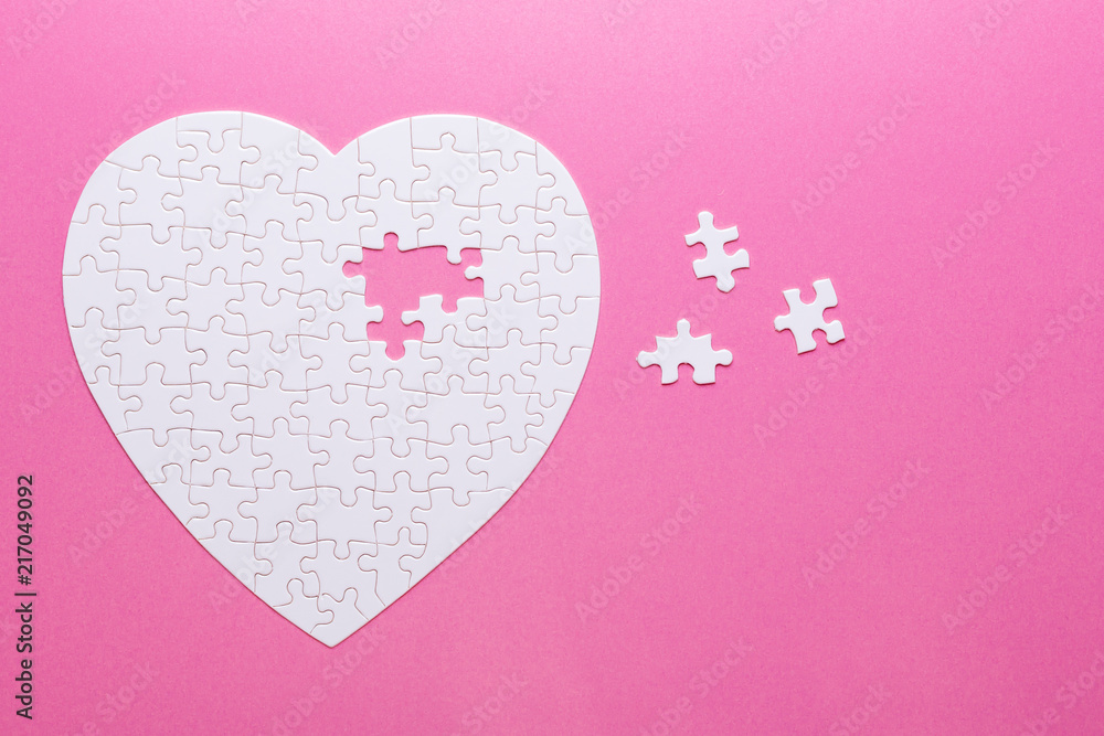 White puzzle heart on pink background. Missing piece. Top view