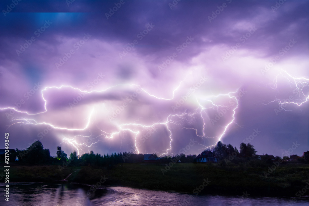 Composition photo of different lightning bolts. Thunderstorm with dramatic clouds. Lots of lightnings over the night village near river bank. Bad weather concept. Composition photo of different lightning bolts. Thunderstorm with dramatic clouds. Lots of lightnings over the night village near river bank. Bad weather concept.