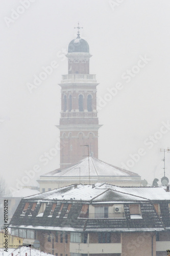Winter unusual aerial landscape of Rovigo in Veneto in the Po valley, Italy. During a snowfall the city roofs got white even the historic landmark as the Rotonda church and its bell tower photo