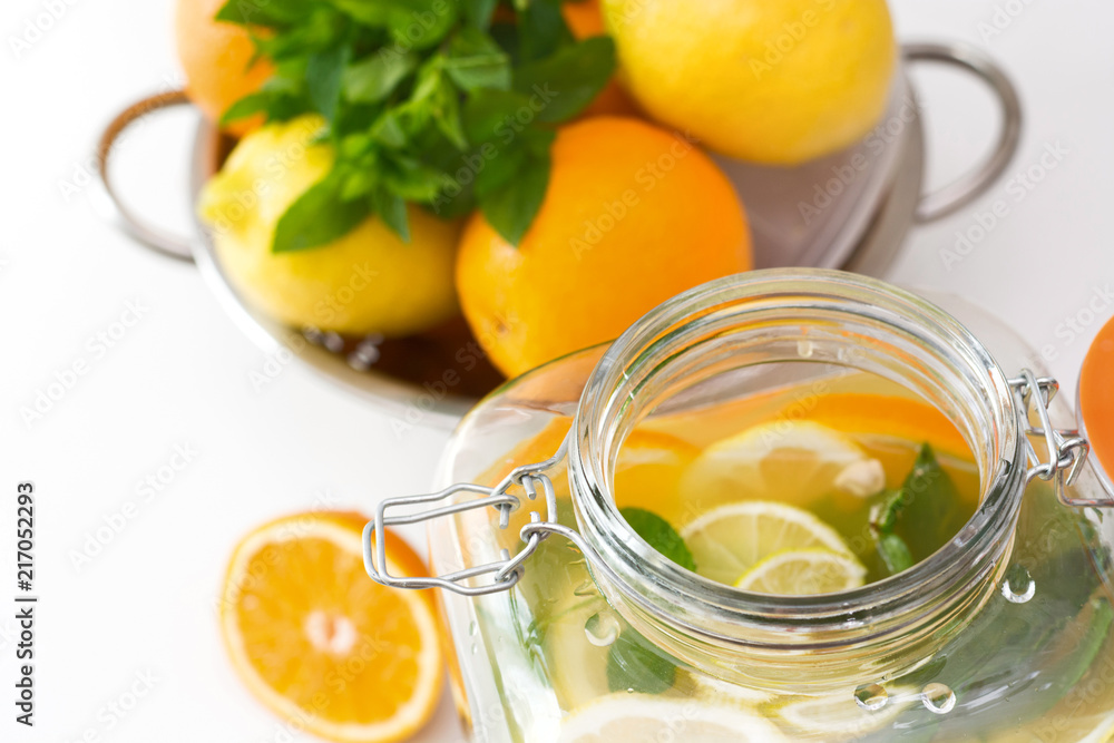 Healthy lemonade in mason jar with lemon, orange and mint on white table. Close up. Healthy lemonade in mason jar with lemon, orange and mint on white table. Close up.