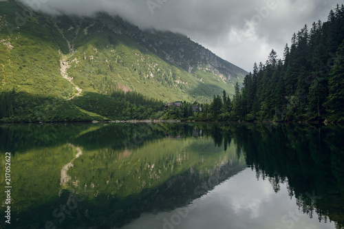 Foggy green mountain forrest and hills with a reflection on the lake, morskie Oko in High Tatras, Zakopane, Poland