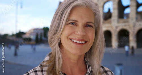 Canvas Print Smiling white female senior enjoys herself in front of Roman Colosseum