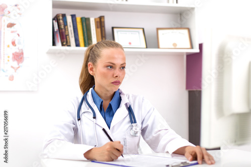 Young female doctor in uniform in doctor's ofice writting a document