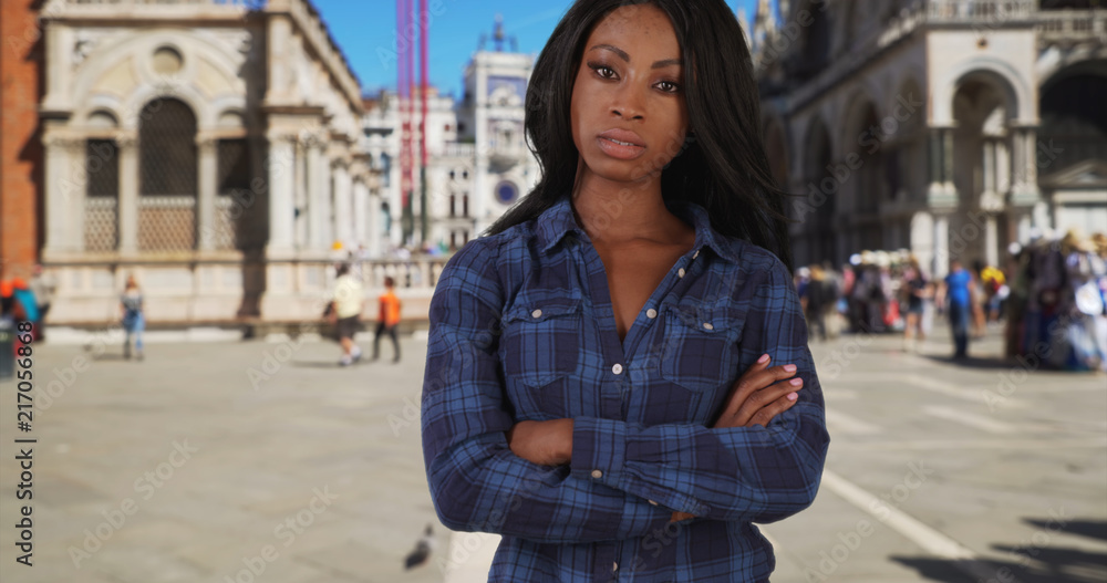 Young pretty black woman standing in St Marks Square with arms crossed