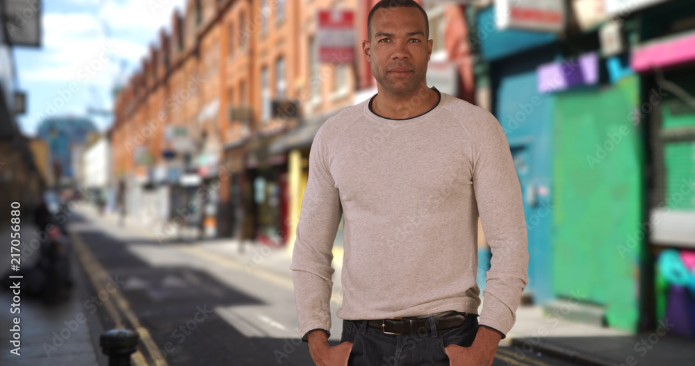 Fototapeta premium Bold young African-American man poses confidently in urban setting