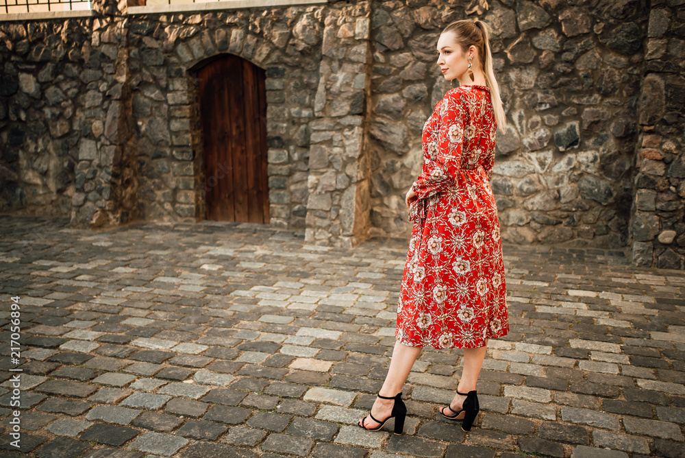 Beautiful young girl in a red dress outdoors, portrait of a stylish woman