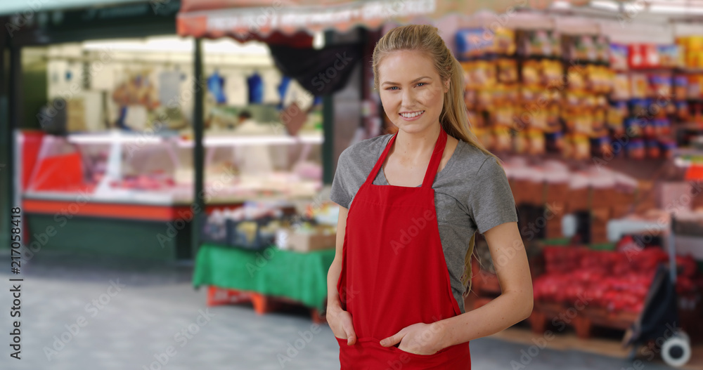 Female Caucasian grocer standing happily at outdoor market