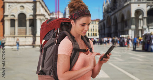 Vacationing white female backpacker checking mobile device at St Marks Square © rocketclips