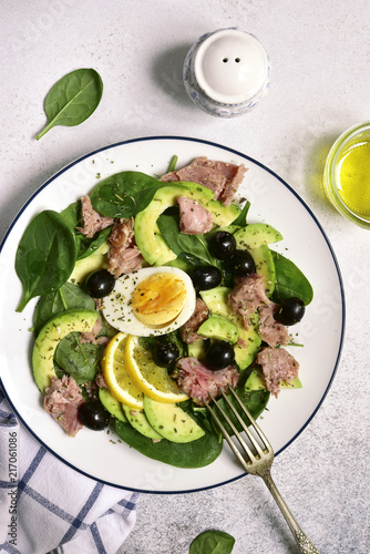 Avocado spinach salad with tuna, boiled eggs and olive oil.Top view.