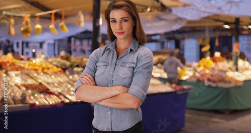 Caucasian female posing sternly with arms folded at outdoor market