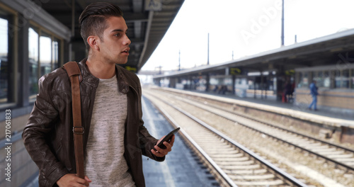 Handsome millennial Latin male at the train station hailing a ride