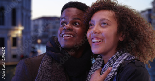 Attractive black tourist couple sightseeing by the Grand Canal in evening