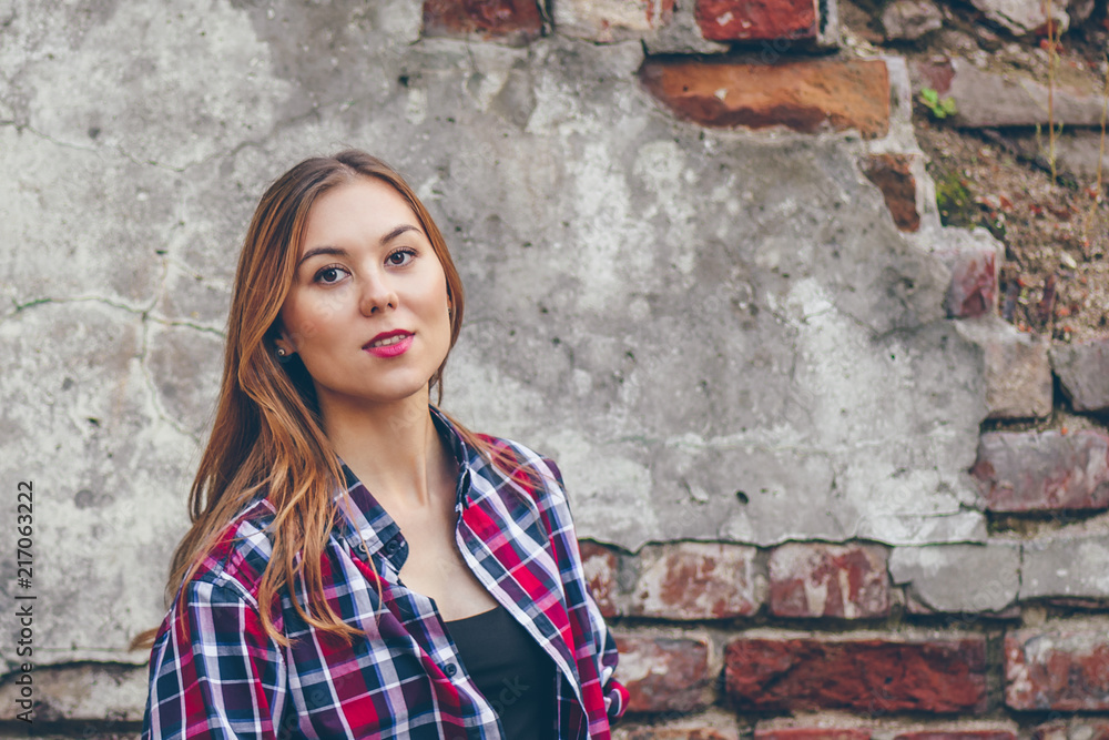 Beautiful girl is standing against brick wall