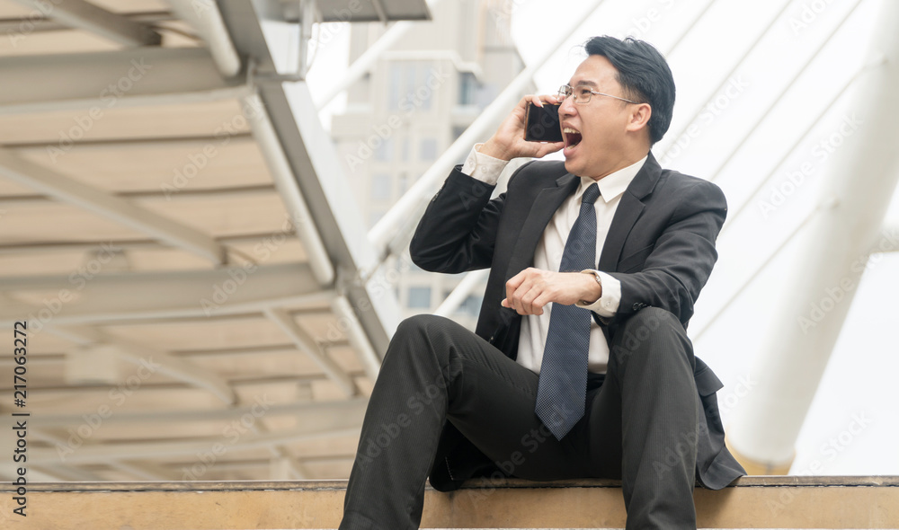 Attractive businessman talking Smartphone with colleague in city background. Business people talk on cell phones absolutely dissatisfied with the agreement. Attractive businessman talking Smartphone with colleague in city background. Business people talk on cell phones absolutely dissatisfied with the agreement.