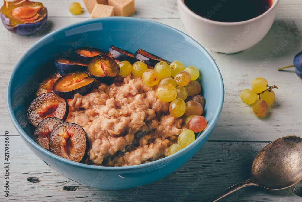 Fototapeta premium Porridge with fresh plum, green grapes and cup of coffee.