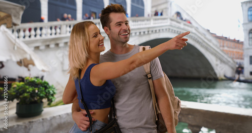 Portrait of happy tourist couple sightseeing by the Rialto Bridge in Venice