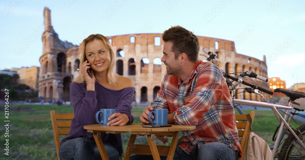 Happy couple relaxing outdoors with coffee near the Coliseum in Rome