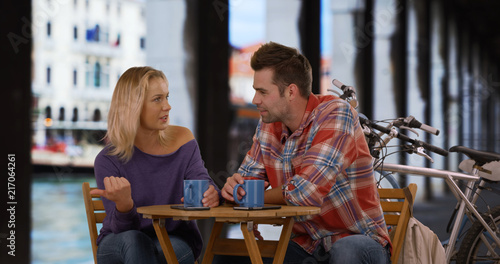 Attractive man and woman sit by the Grand Canal drinking coffee