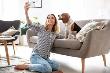 Young woman taking selfie with her dog at home