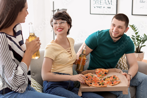 Young people having fun party with delicious pizza indoors