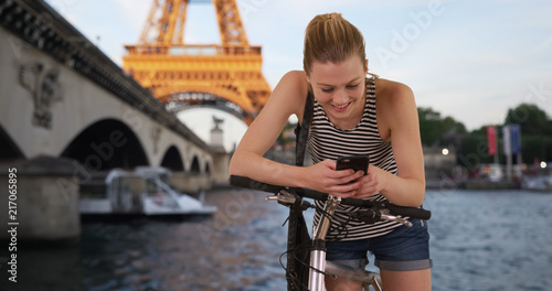 Pretty millennial girl in summer shorts using cellphone in Paris