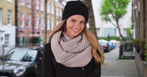 Smiling portrait of Caucasian woman in cozy hat and scarf outside © rocketclips