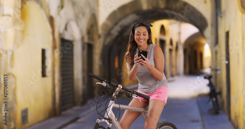 Cute Latina woman on her bike messaging to a friend on smartphone