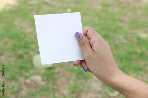 Hand hold white blank business card on green background