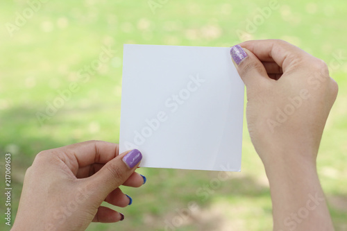 Hand hold white blank business card on green background