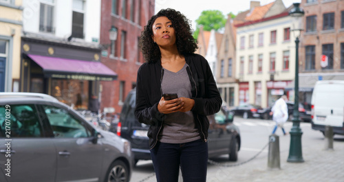 Pretty black woman walking through the city stopping to use her phone © rocketclips