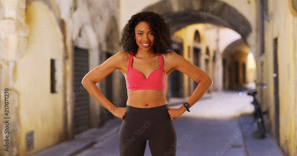 Black woman athlete in Florence flexing her arm muscles smiling at camera